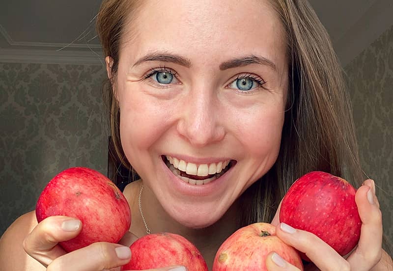 Daria Arofikina tenant des pommes devant son visage