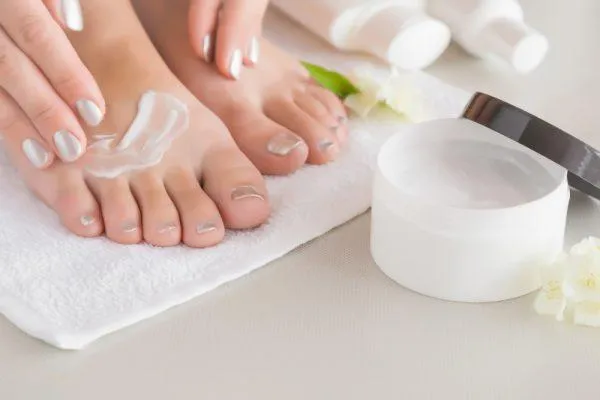 A Close Up Of A Woman'S Feet Applying Cream