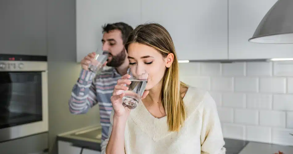 Dont Forget The Basics Hydration And Patience Two Adults Drinking Glasses Of Water In A Bright Kitchen, Showing The Importance Of Hydration For Better Insulin Effectiveness And Blood Sugar Control.